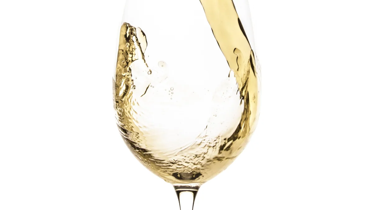 Droge witte wijn wordt ingeschonken in een wijnglas
